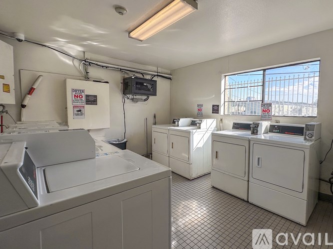 A white room with a large printer and a smaller one to the right, a window with bars on it and a sign on the wall.