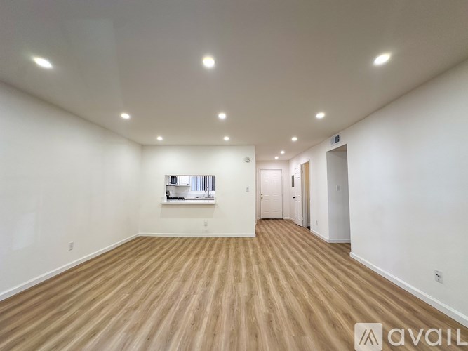 A spacious room with wooden flooring and white walls.