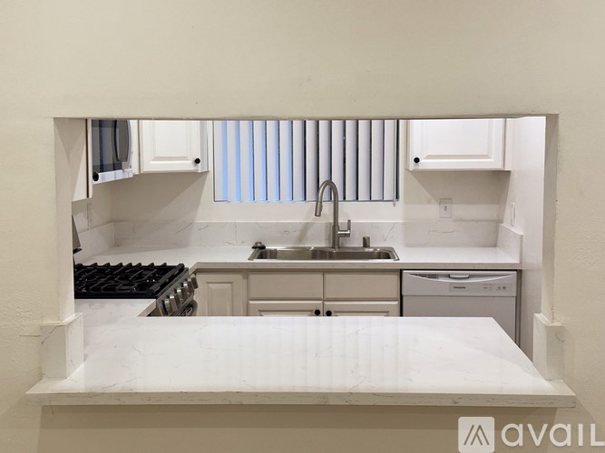 A kitchen with a marble countertop and stainless steel appliances.