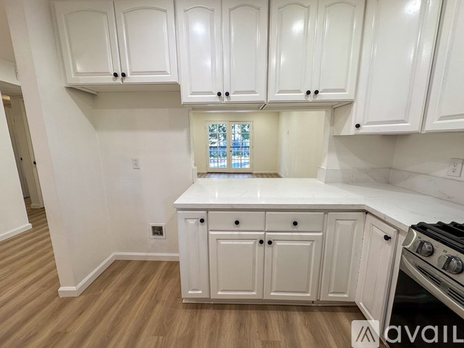 A kitchen with white cabinets and a window.