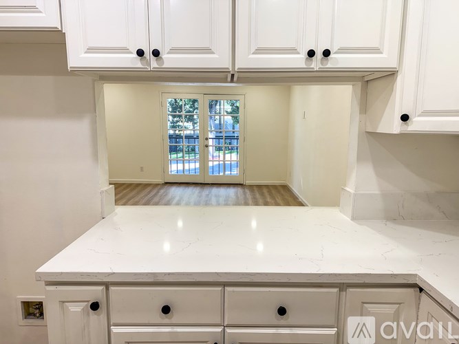 A kitchen with white cabinets and a marble countertop.