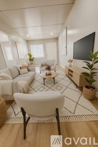 A living room with a white sofa set, a coffee table, and a flat screen TV mounted on the wall.