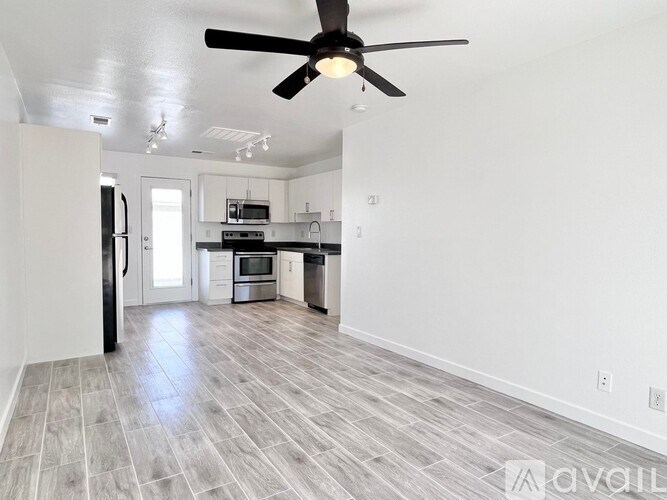 A spacious kitchen and living room with a ceiling fan and hardwood flooring.