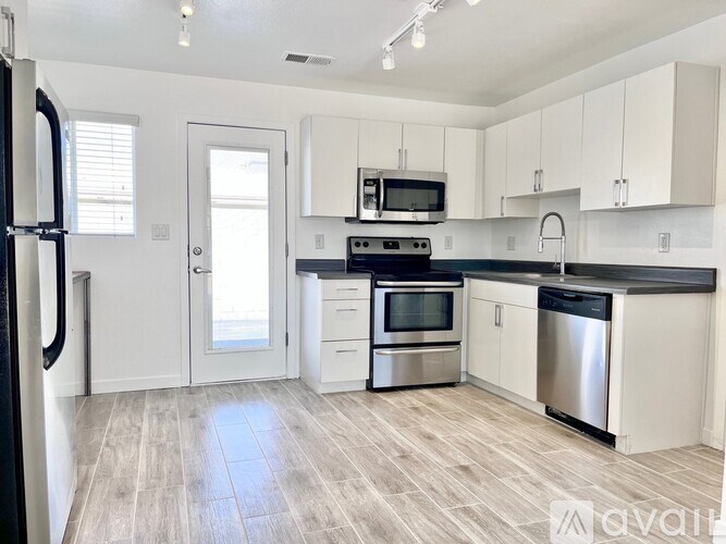 A kitchen with white cabinets and a black countertop.