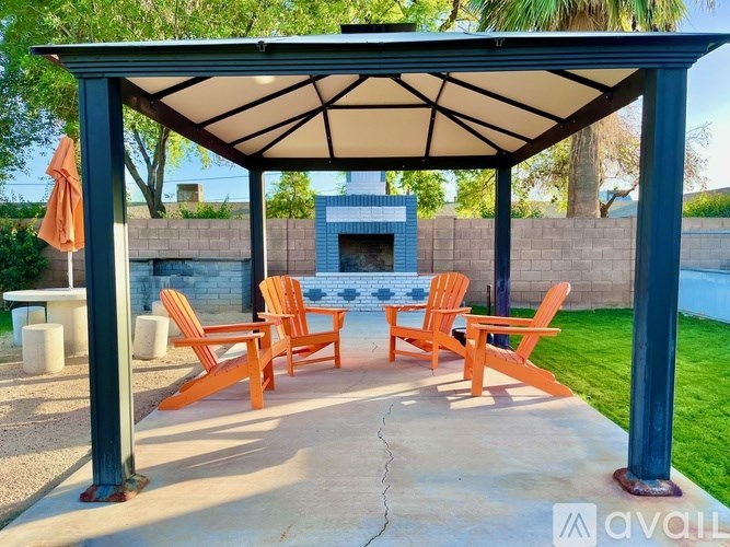 A patio with a fireplace and chairs under a canopy.
