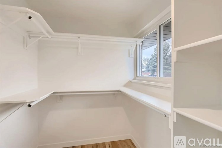 A white kitchen with a window and a shelf.