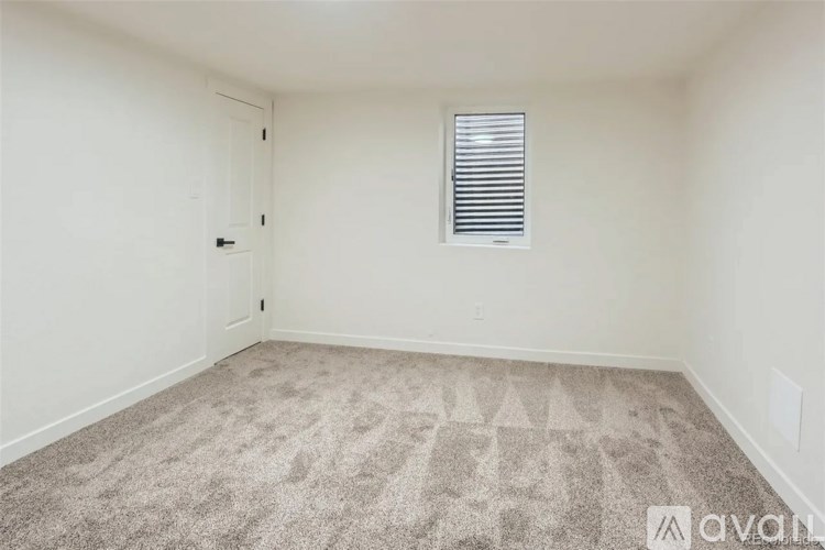 A room with a carpeted floor and a window with blinds.
