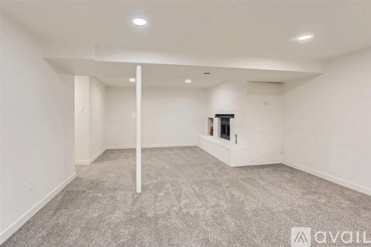 A spacious room with a carpeted floor and a fireplace.