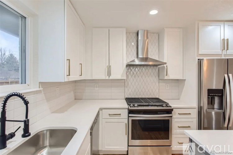 A kitchen with white cabinets and a stainless steel refrigerator.