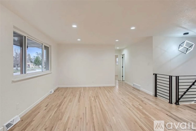 A spacious room with wooden flooring and a skylight.