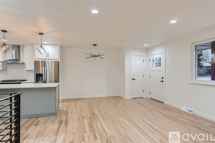 A kitchen with a stainless steel refrigerator and wooden flooring.