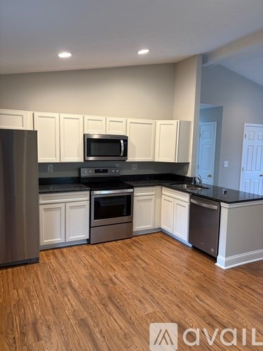 A kitchen with wooden floors and white cabinets.