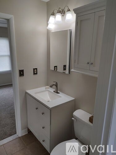 A bathroom with a sink, toilet and mirror.