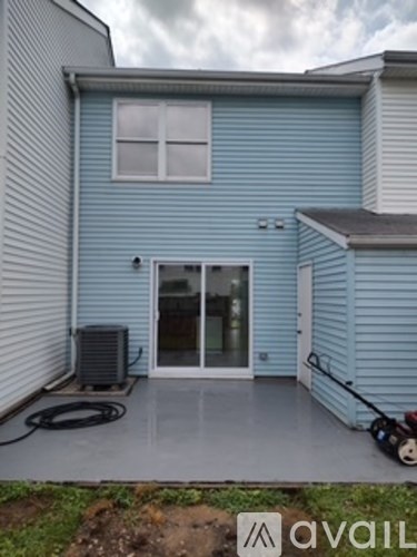 A blue house with a patio and a hose on the ground.