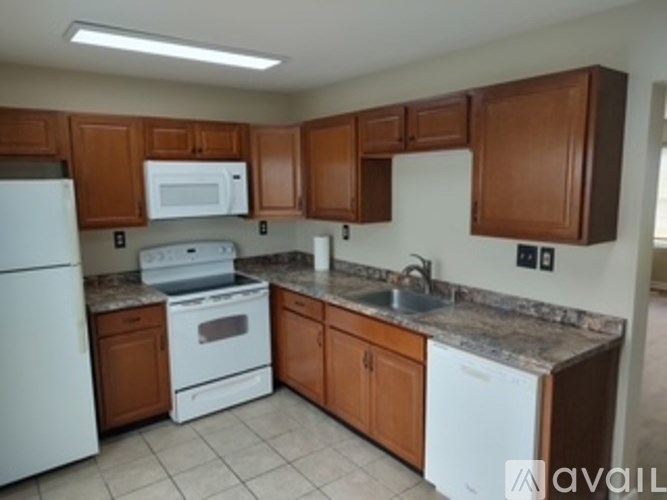 A kitchen with brown cabinets and white appliances.