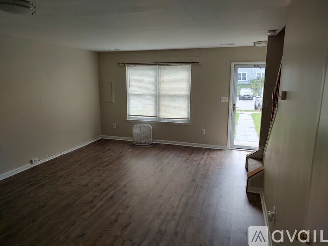 A room with wooden flooring and a window with blinds.