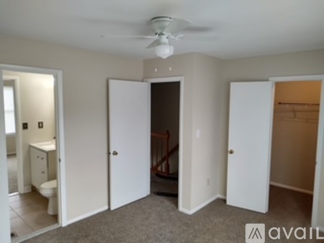 A room with a fan on the ceiling and a toilet in the corner.