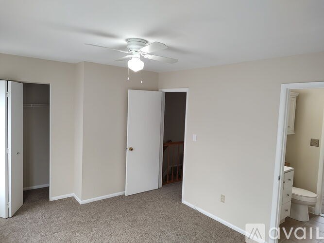 A room with a ceiling fan and carpeted floor.