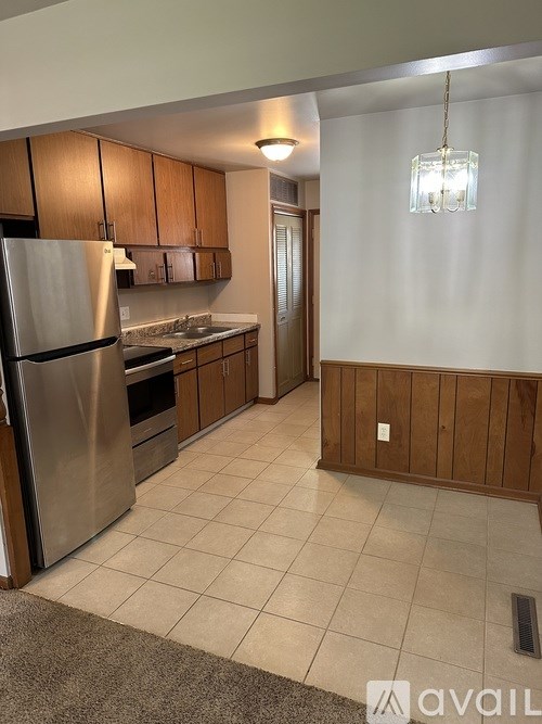 A kitchen with a refrigerator, cabinets, and a sink.