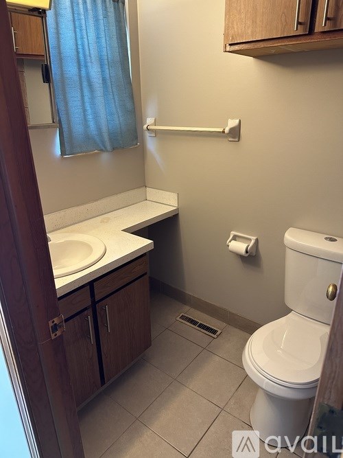 A bathroom with a toilet, sink, and a window with a blue curtain.