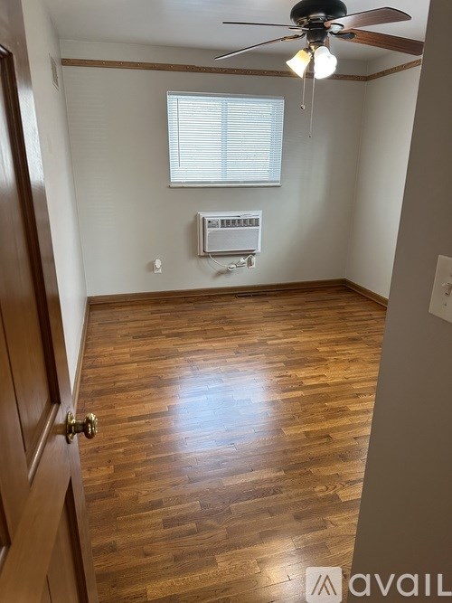 A room with a ceiling fan and a window with blinds.