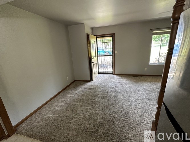 A carpeted room with a door leading to a balcony.