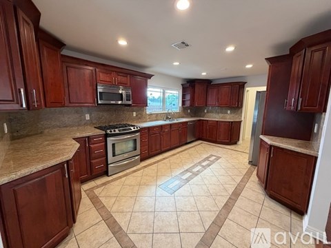 A kitchen with brown cabinets and a tiled floor.