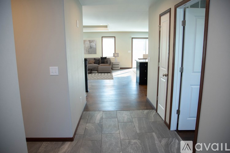 A hallway with a tiled floor leads to a living room.
