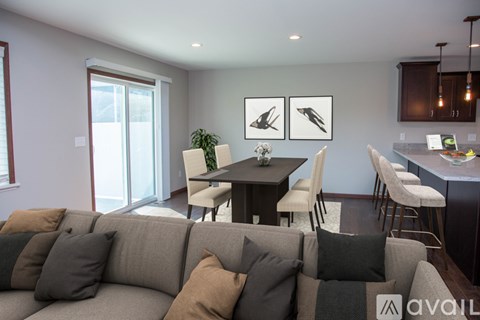 A living room with a grey couch and a dining table with chairs.