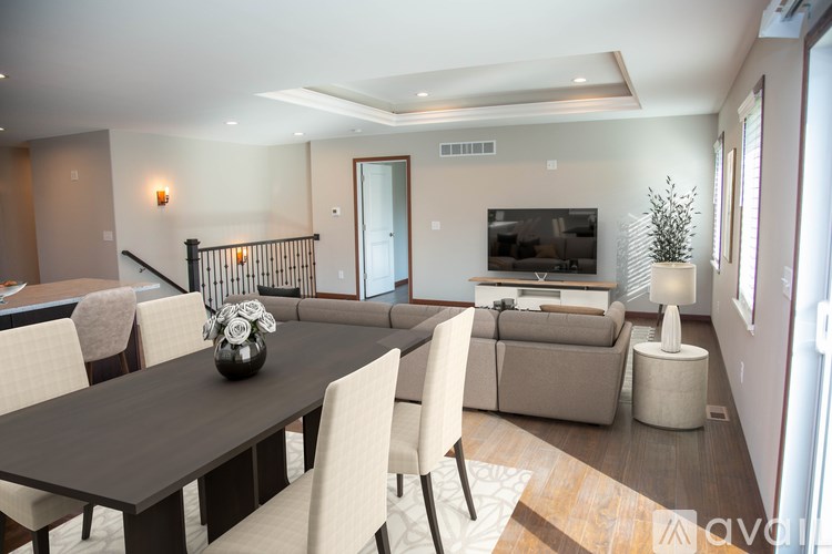A modern dining room with a dark wood table and white chairs.