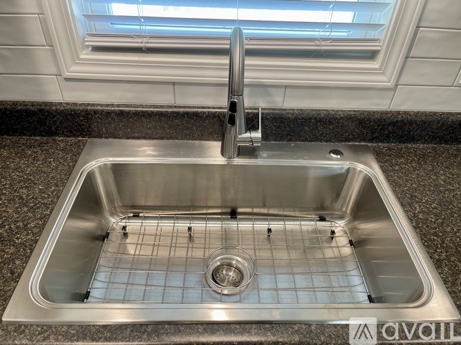 A stainless steel kitchen sink with a grid drain.
