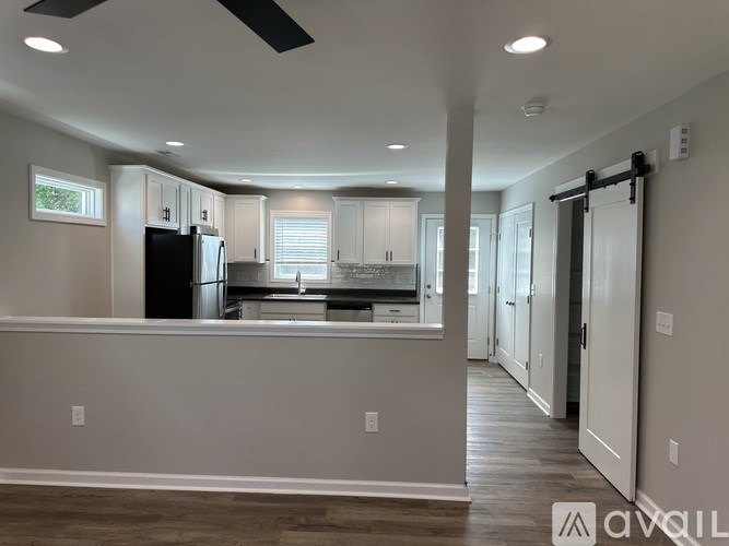 A modern kitchen with a black refrigerator and white cabinets.