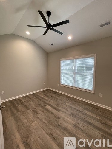A room with a ceiling fan and a window with blinds.