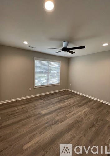 A room with a ceiling fan and wooden flooring.
