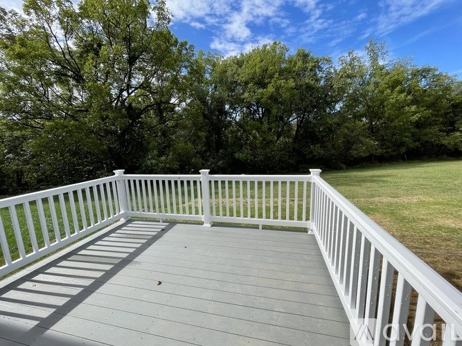 A white railing on a wooden deck overlooks a grassy area.