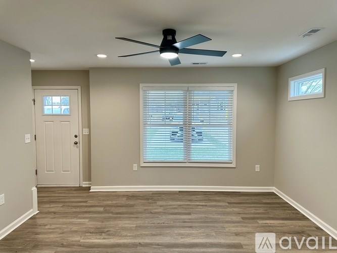 A room with a ceiling fan and a window with blinds.