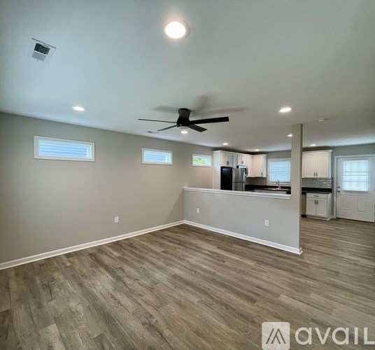 A spacious room with a ceiling fan and lighting fixtures.