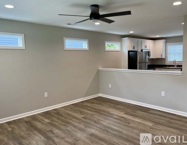 A spacious kitchen and living room with wood flooring and a ceiling fan.