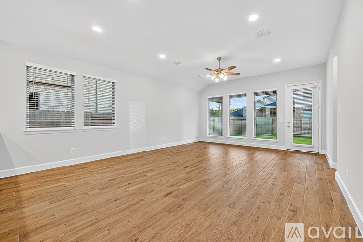 A spacious room with wooden flooring and a ceiling fan.