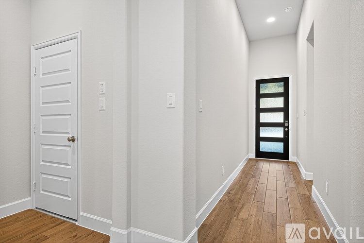 A hallway with a white door and a black door at the end.