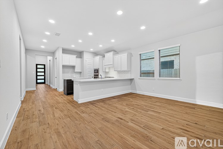 A spacious kitchen with wooden floors and white cabinetry.