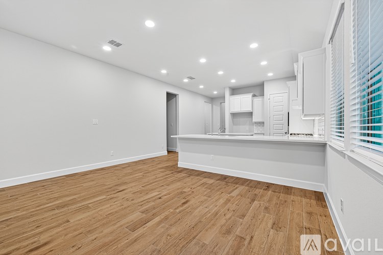 A spacious room with wooden flooring and white walls.