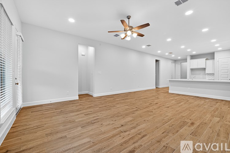 A spacious room with wooden flooring and a ceiling fan.