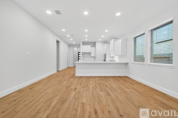 A spacious room with wooden flooring and white walls.