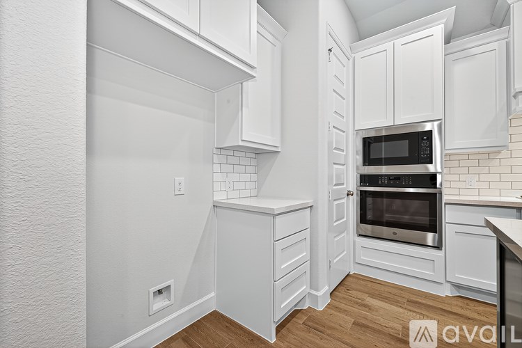 A kitchen with white cabinets and a stainless steel oven.