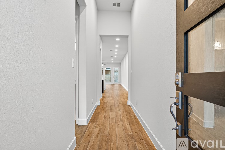 A long hallway with wood floors and white walls.