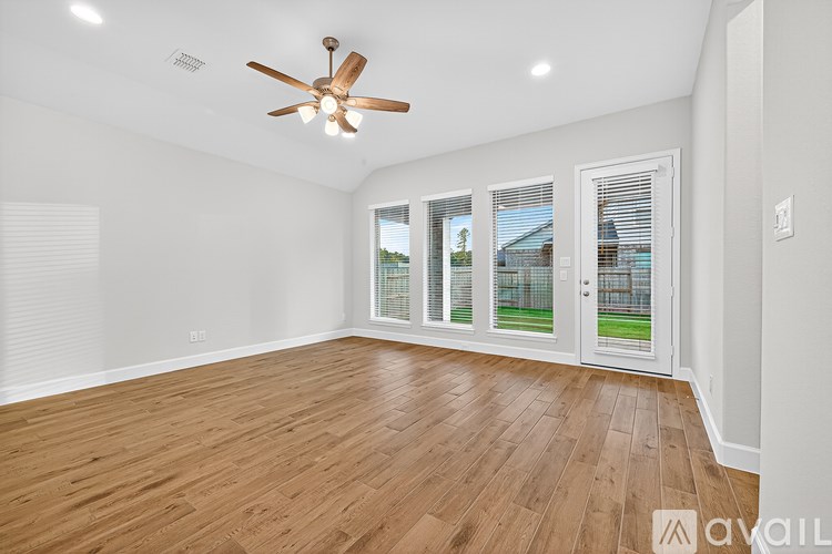 A room with a ceiling fan and sliding glass doors.