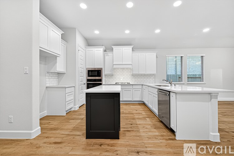 A kitchen with white cabinets and a black island.
