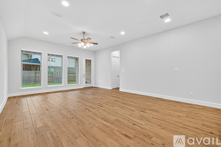 A spacious room with wooden flooring and a ceiling fan.