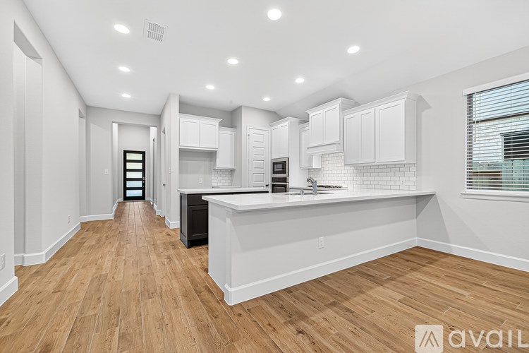 A spacious kitchen with white cabinets and a wooden floor.